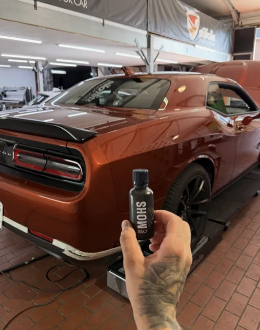 Oranger Dodge Challenger mit Coating-Flasche bei Fahrzeugpflege Hannen